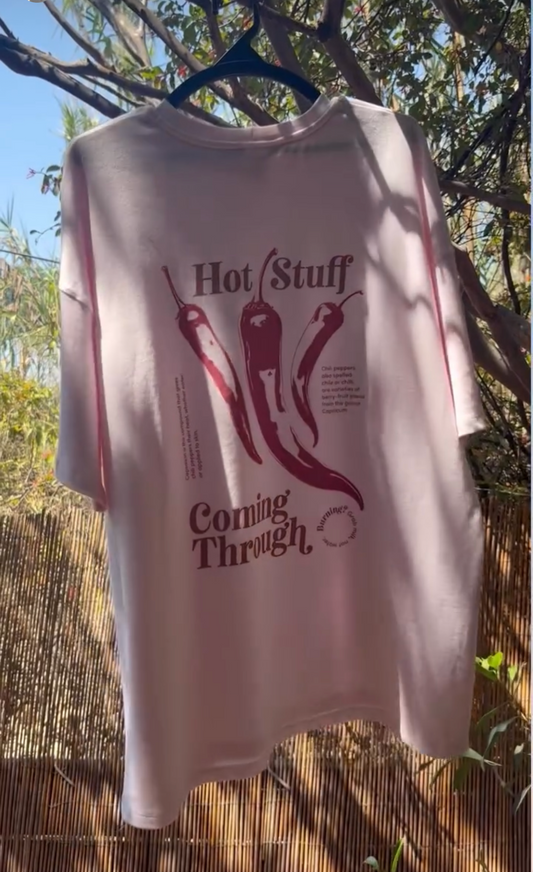 Pink t-shirt with graphic design and text hanging outdoors.